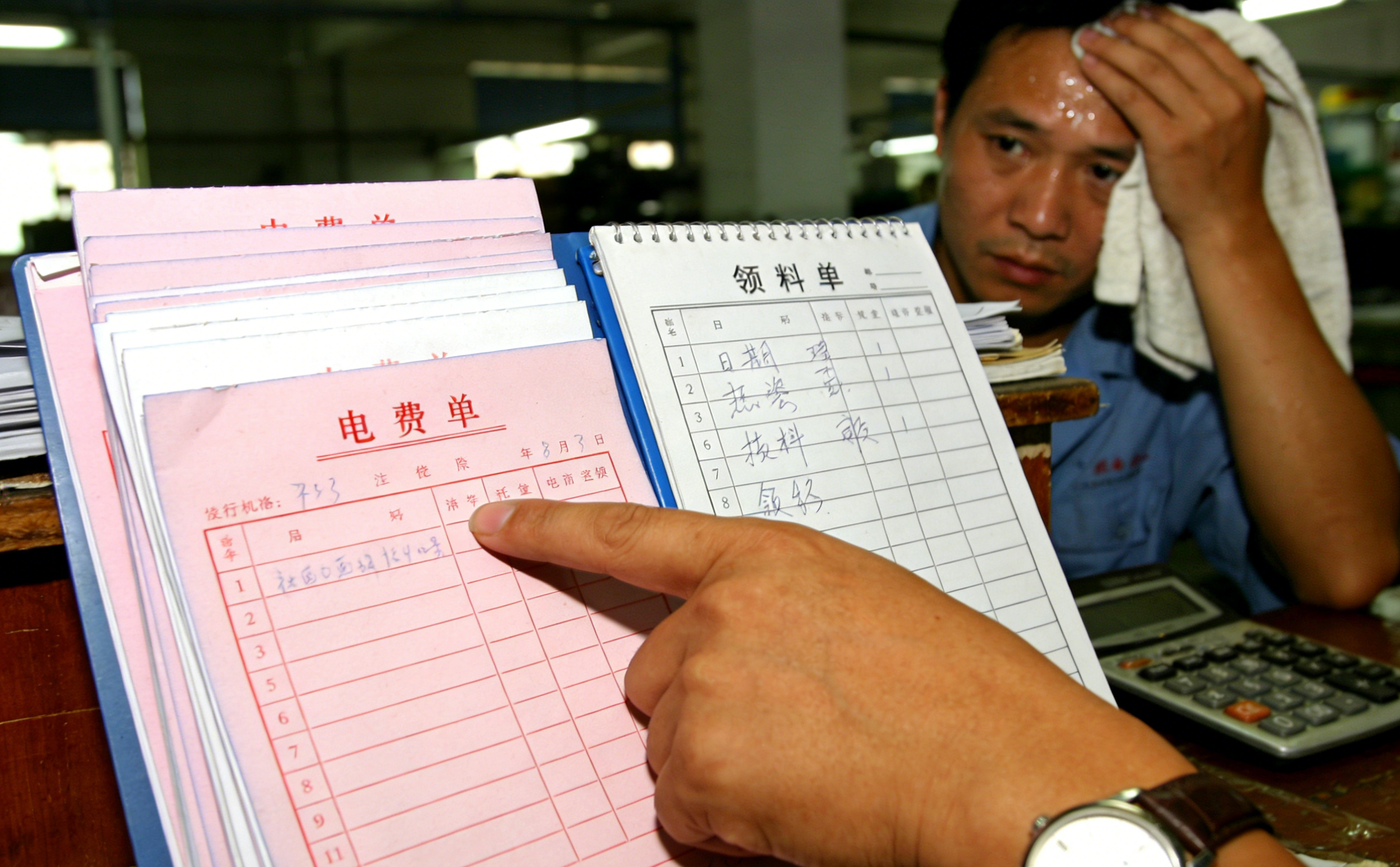 Close-up of auditor analyzing Chinese electricity bills and material logs in a Dongguan factory to verify claimed manufacturing capacity